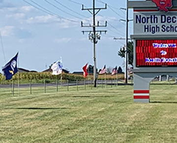 Flags on display beside the road in front of North Decatur High School
