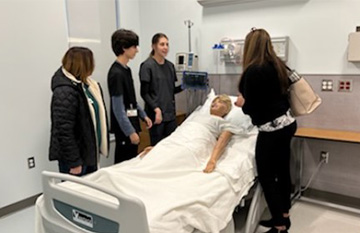 Students and adults looking at a fake patient