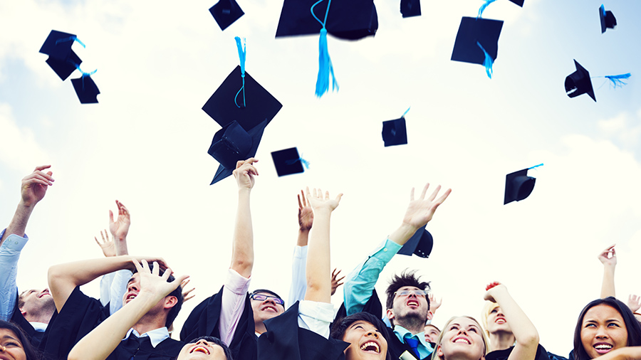 Graduates celebrating and throwing graduation caps in the air