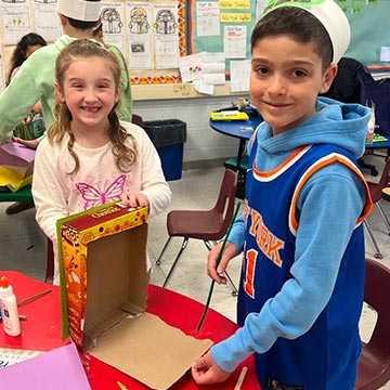 Two students working on a cereal box project in class