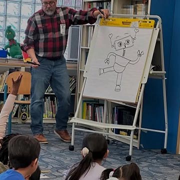 Teacher showing students a drawing of a robot