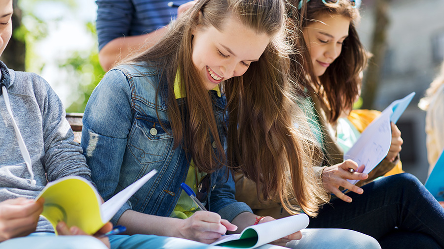 Happy high school students outside working together