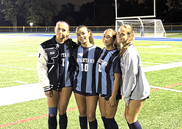 Notebook on desk in the classroom Girls soccer team members on the field
