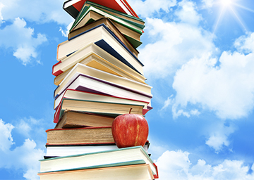 Notebook on desk in the classroom Stack of books with red apple