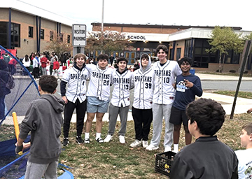 Group of students posing for a picture outside front of school building