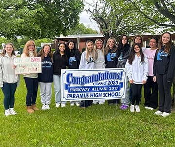 Students behind a sign that reads Congratulations! class of 2025 Parkway Alumni 2017 Paramus High School