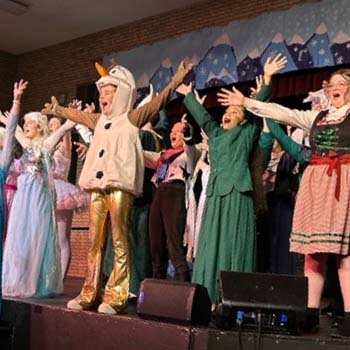 Notebook on desk in the classroom Students singing in christmas outfits
