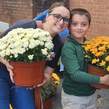 Adult and student holding flowering plants