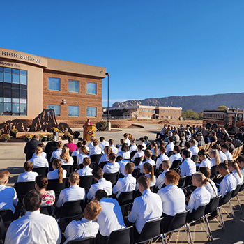 Students sitting outside the Masada Jr High School listening to a presentation