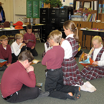 Students sitting and kneeling on classroom floor