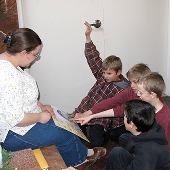 An adult holding a book while four students look at it