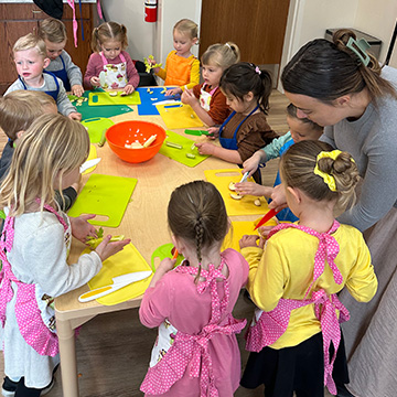 An adult showing young students how to prepare food