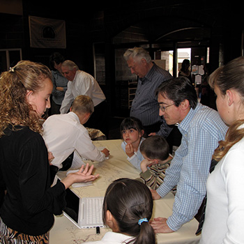 Adults and children getting information from people at tables