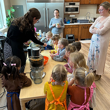 Three adults showing students how to prepare food