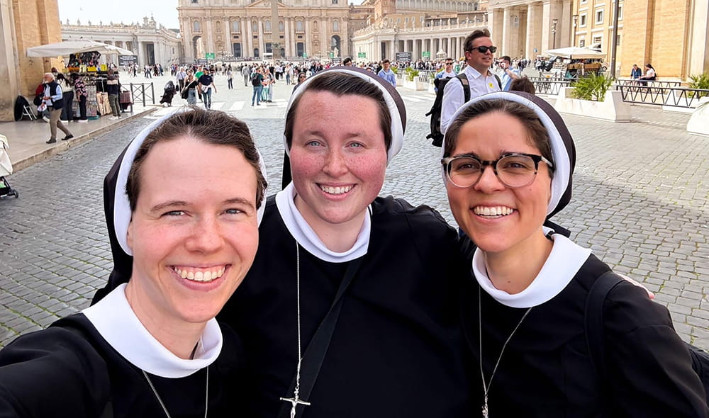Sisters standing together in front of Christus statue