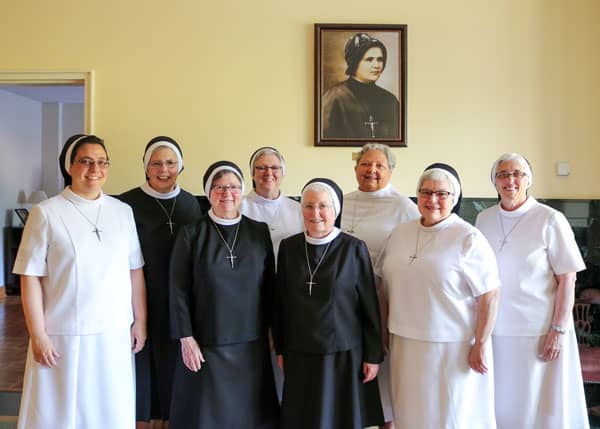 Sisters standing in front of portrait of Mother Clelia