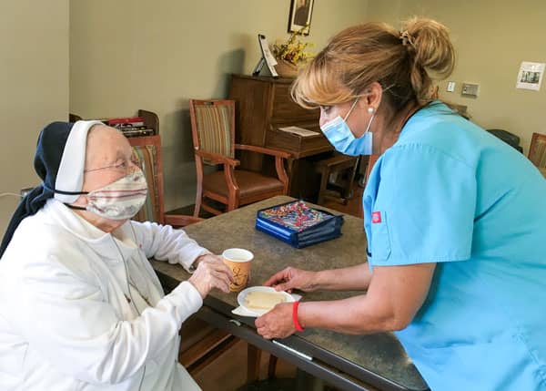 sister in mask being served a snack by a nurse