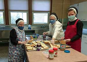 three sisters in masks making sandwiches