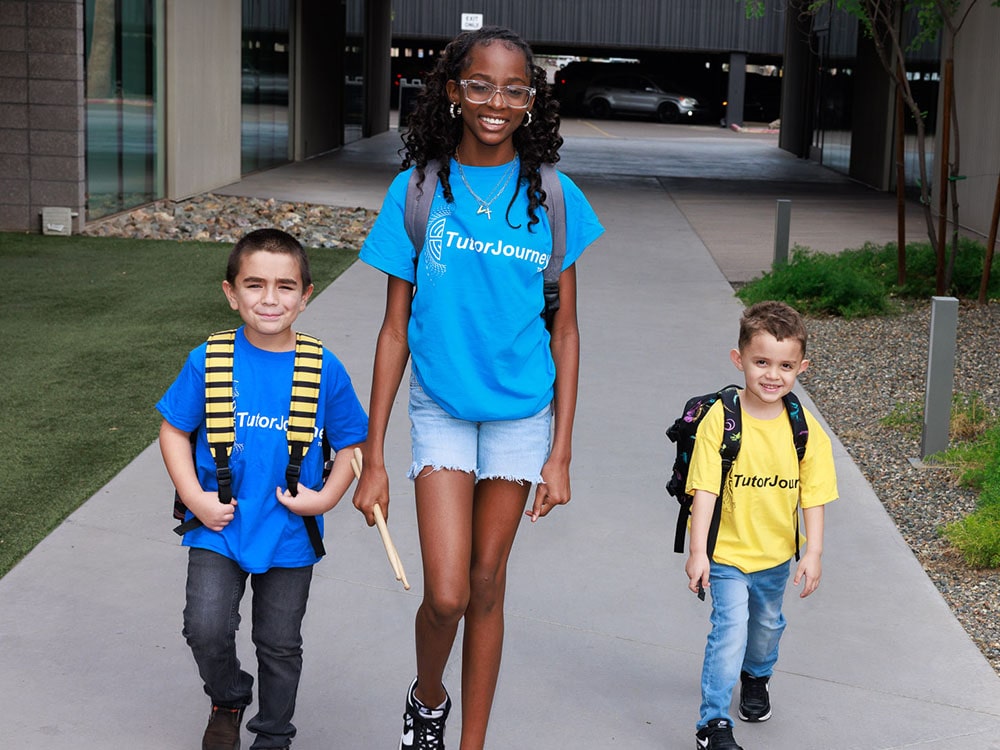 three students standing in front of building smiling