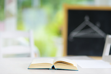 Book on a desk with chalkboard in the background