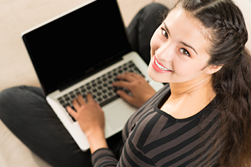Young lady looking up from her laptop and smiling