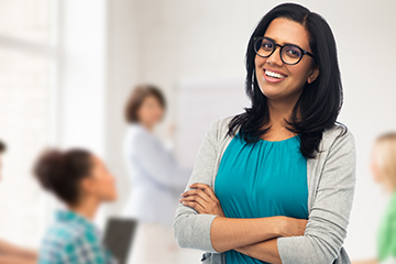 Happy teacher proudly standing in her classroom