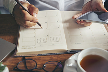 Parent updating personal calendar while looking at school calendar online via mobile phone