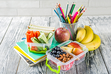 Healthy lunch options next to colored pencils on a desk