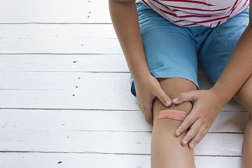 Child sitting on floor with bandage on knee