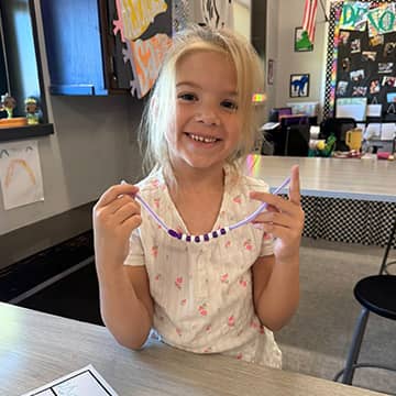 Student showing beads on a pipe cleaner