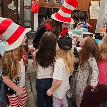 An adult and students, some are dressed as Cat in the Hat