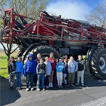 Students lined up beside a large vehicle