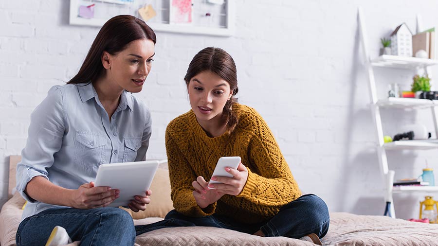 Student looking at her phone with her mother