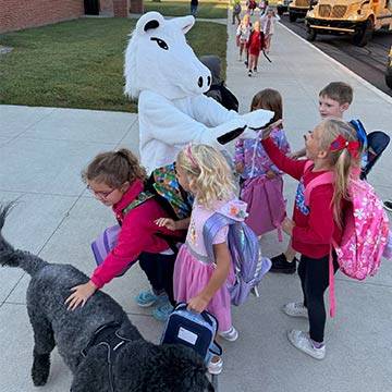 Students arriving at school and giving the mascot high fives
