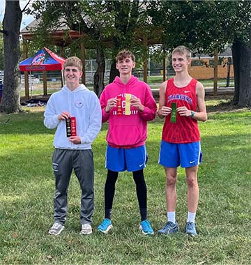 Three student athletes holding awards