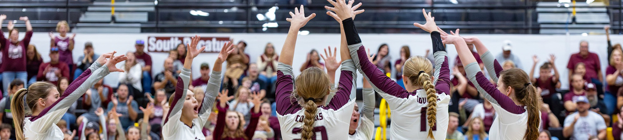 Girls volleyball team and fans cheering on the court