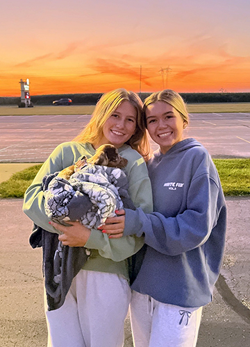 Two girls at a senior event holding a puppy