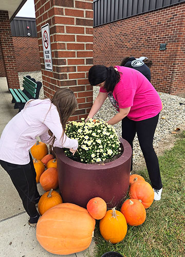 Two students planting flowers outside school yard