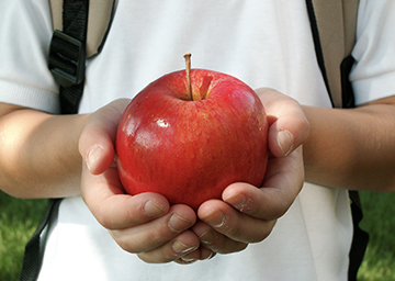 Student holding up a red apple