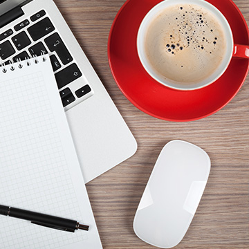 Laptop next to red cup of coffee