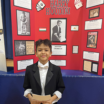 A student's dressed as Harry Houdini in front of a display about him
