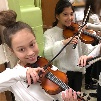 Smiling students playing violins