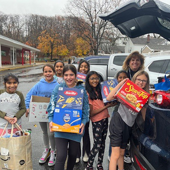 students and a teachers loading food in the back of a car