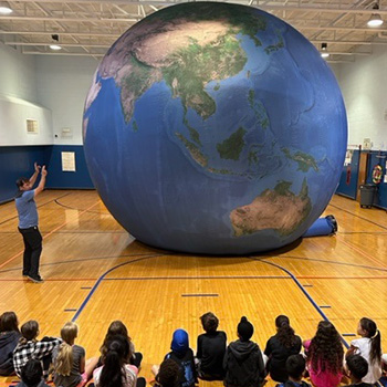 Students looking at a large globe of Earth in the gym