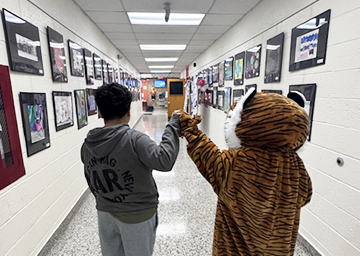 Student fist bumping school mascot as they walk down the school hallway