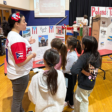 Group of younger students learning about Puerto Rico from an older student during project fair