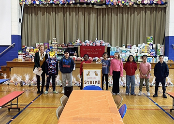 Proud students and teacher in front of food donations