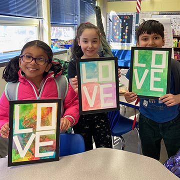 Students holding up their artwork that say LOVE Students holding up their artwork that say LOVE