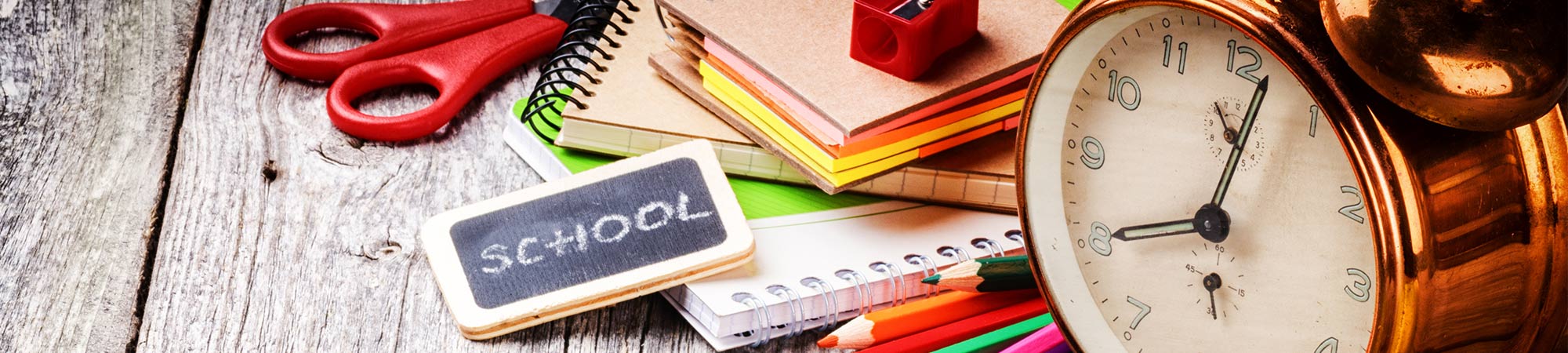 Closeup of an alarm clock and notebooks on a table