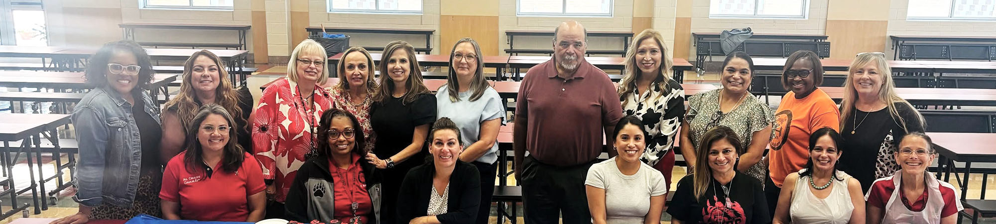 Group of happy staff members posing for a photo in the school cafeteria